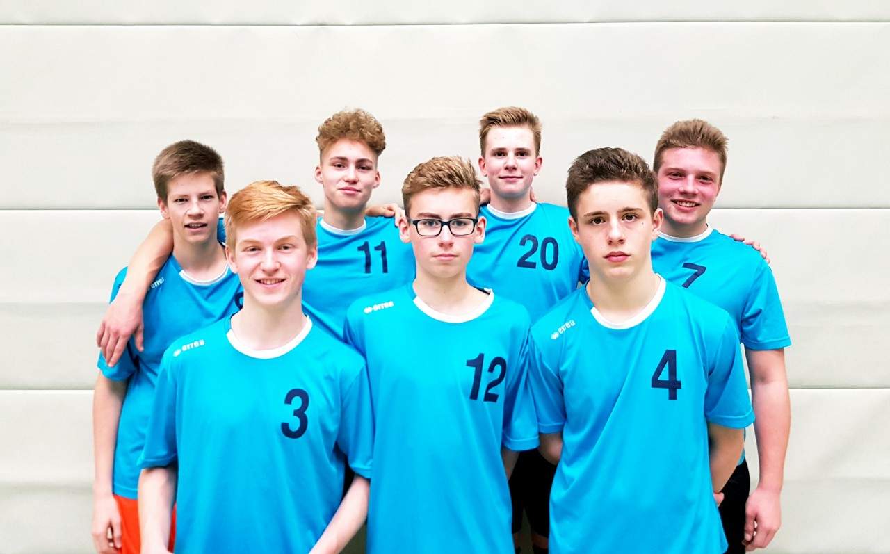 Die Schulmannschaft in hellblauen Trikots stellt sich in der Sporthalle zum Gruppenbild auf