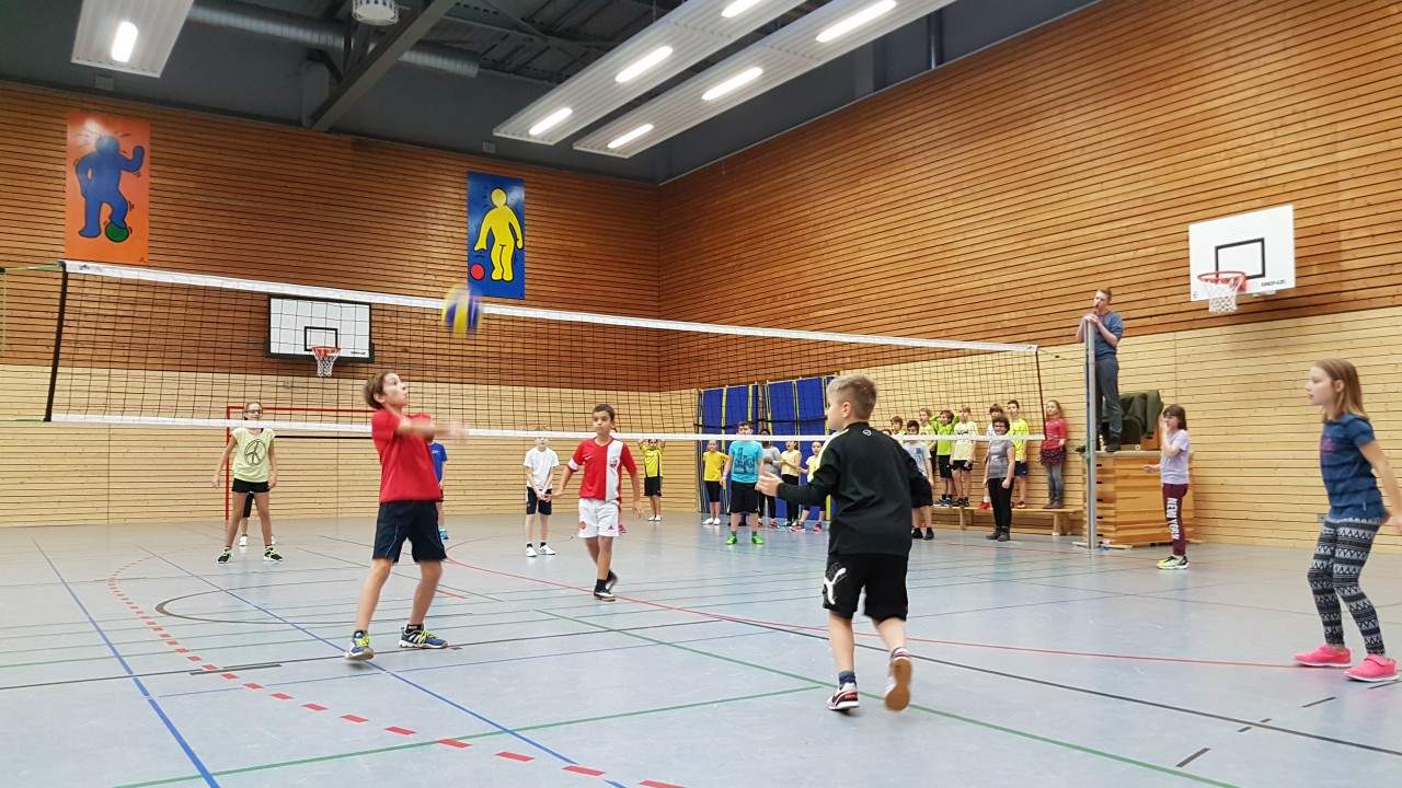 Volleyballspiel in der Sporthalle, mehrere Felder mit Netzen nebeneinander