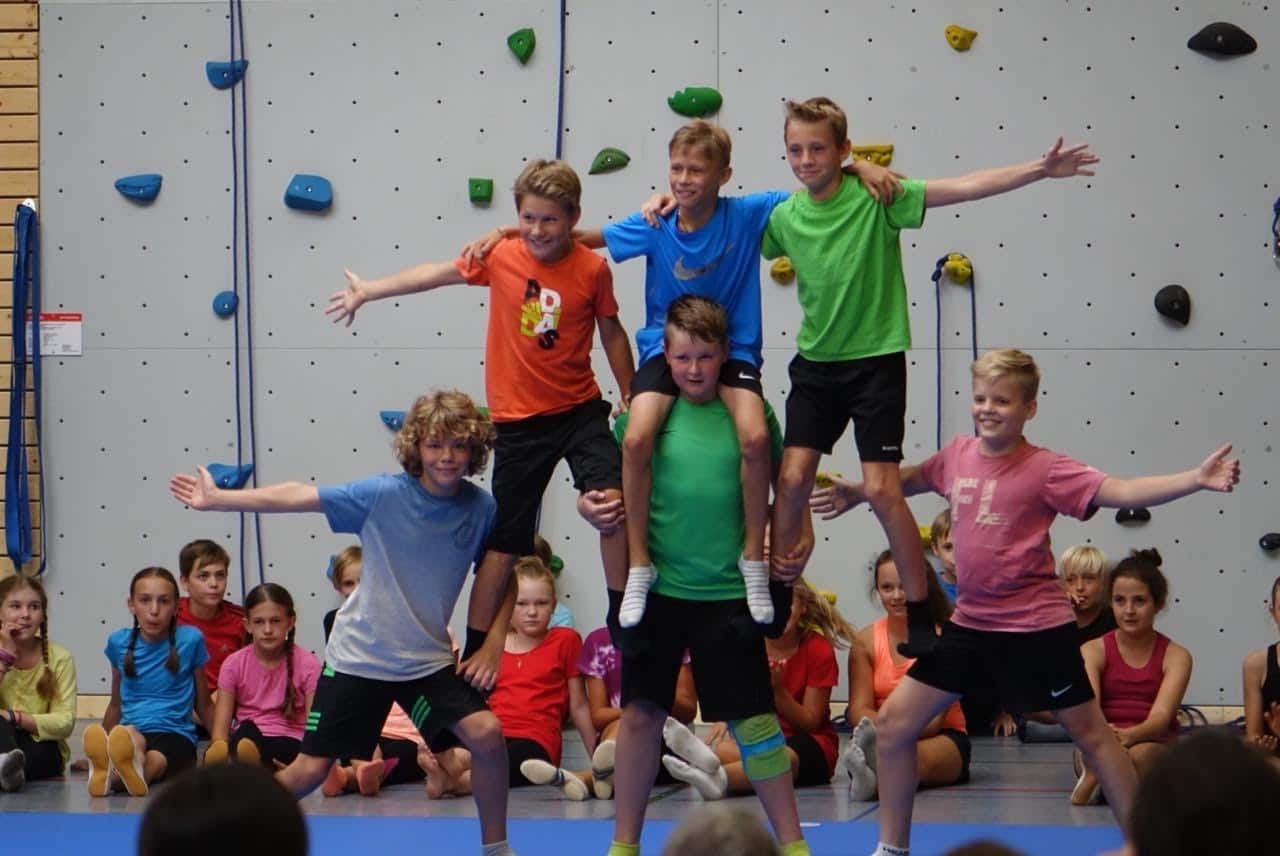 Kinder springen bei der Sportgala vor der Kletterwand in die Luft