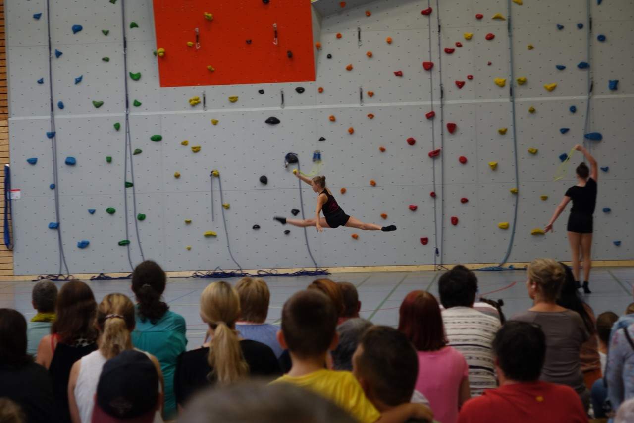 Eine Kletterin hoch an der Wand, unten schaut das Publikum zu