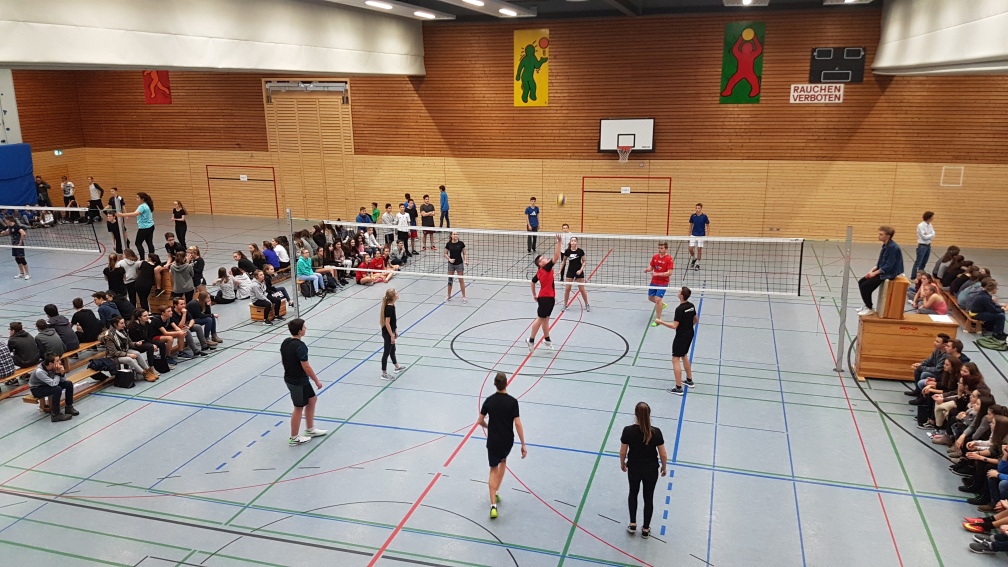 Volleyballspiel in der Halle, an der Wand sitzen wartende Mannschaften