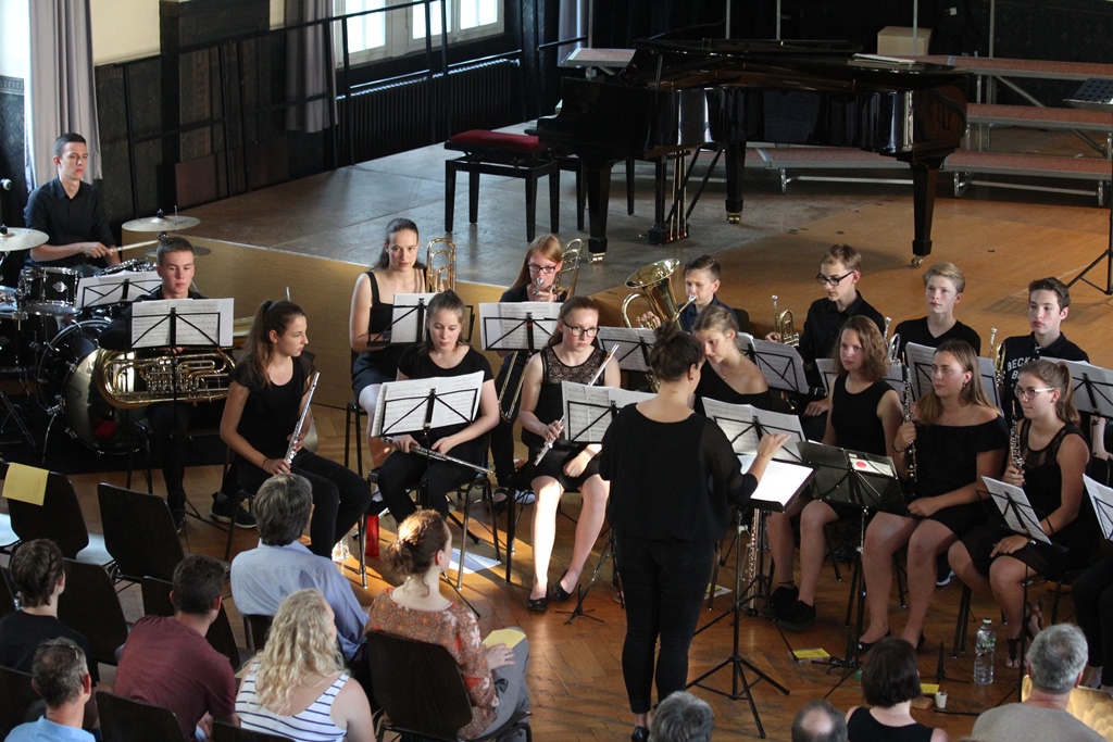 Orchester in Schwarz beim Konzert, im Vordergrund das Publikum