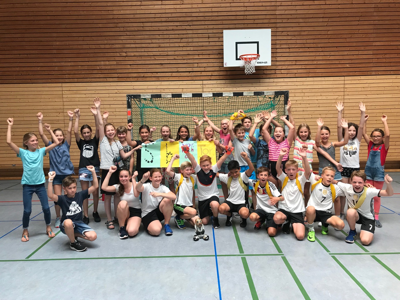 Zwei Mannschaften jubeln in der Sporthalle unter dem Basketballkorb
